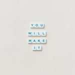 Motivational phrase 'You Will Make It' made from Scrabble tiles on a neutral background.